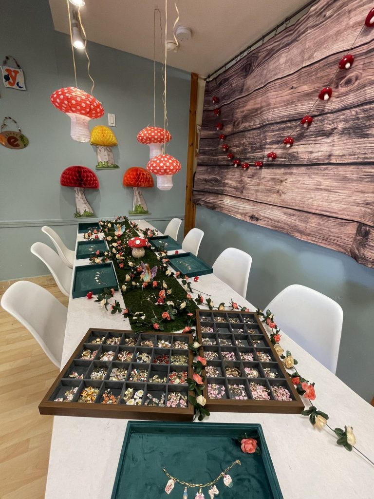A fairy-garden party table with charm trays and mushroom decorations