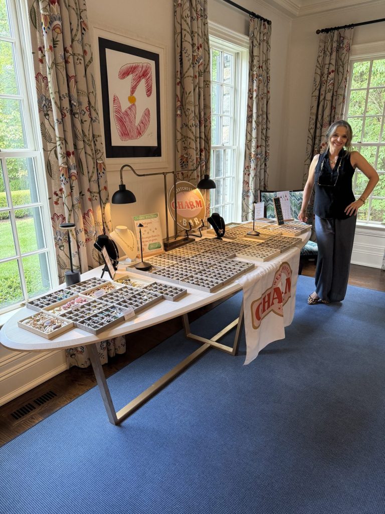 A Charm Bar host beside an oval table of charm trays