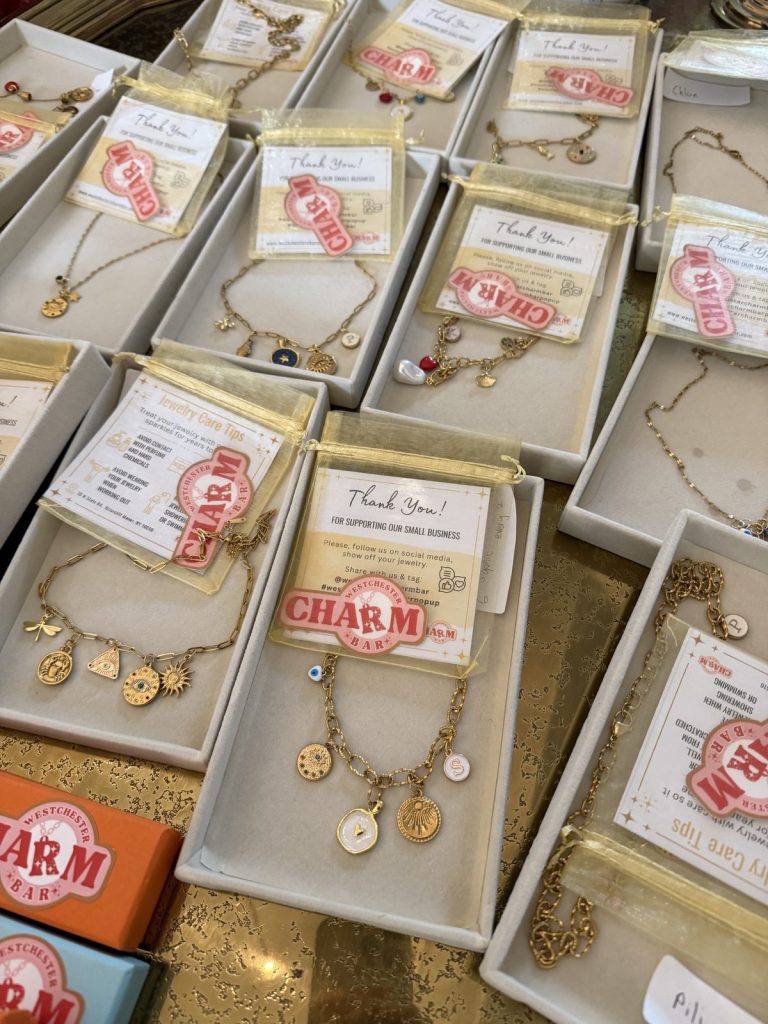 Finished charm necklaces and bracelets in gift boxes with thank-you cards at a Mobile Charm Bar event