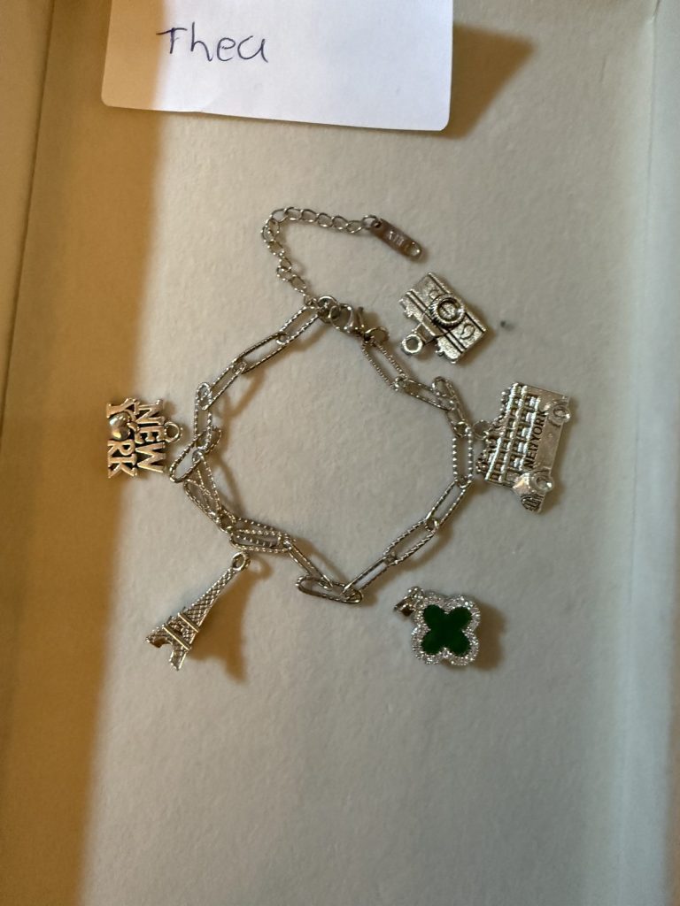 Silver charm bracelet with a camera, an Eiffel Tower and a green clover