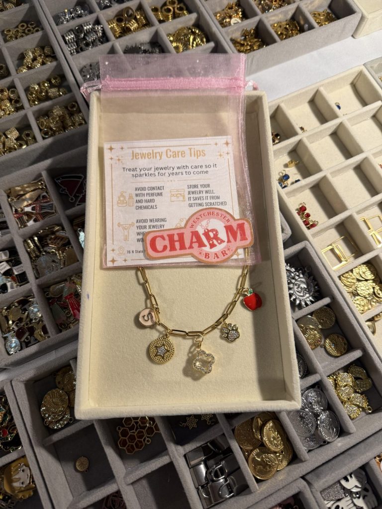 A finished charm bracelet in its gift box on top of the charm trays