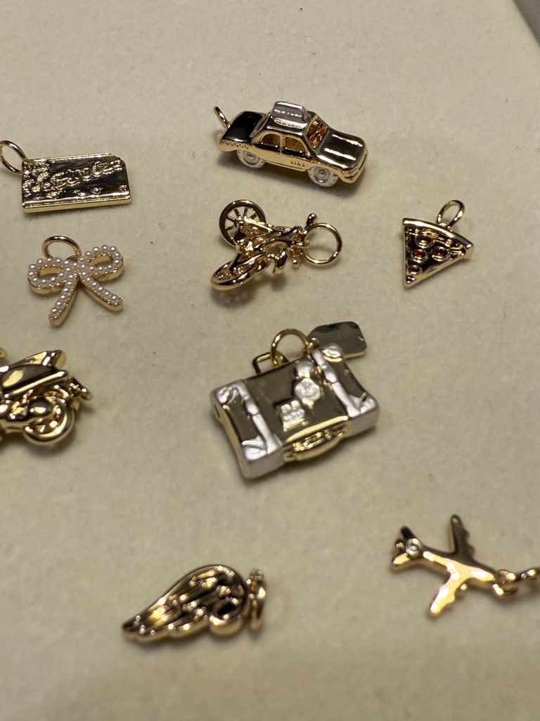 Gold travel charms: a taxi, a suitcase, an airplane and a pizza slice