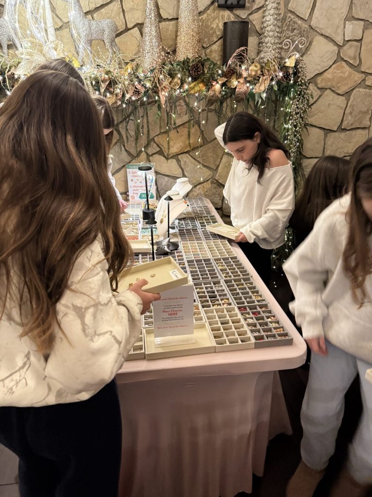Girls choosing charms in front of a flower-covered stone wall