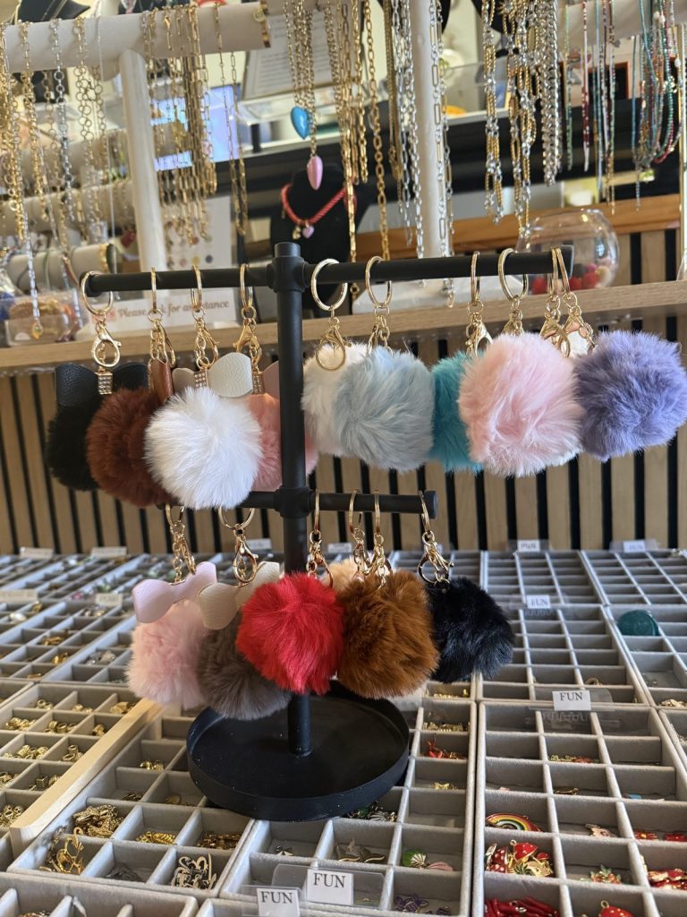 Pom-pom keychains hanging above the charm trays