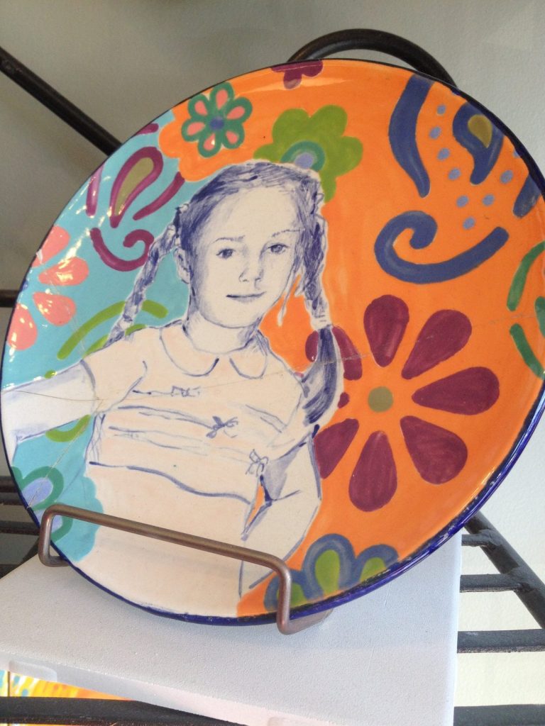 Hand-painted round plate portrait of a young girl on a bright orange and turquoise floral background