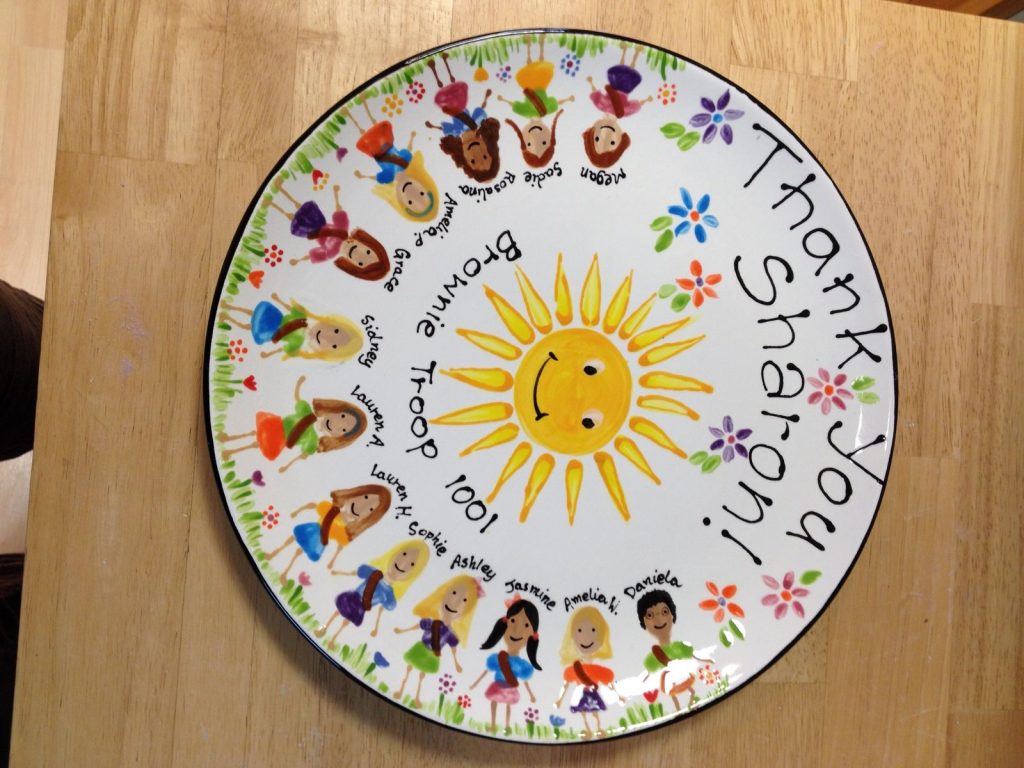 Round Brownie troop thank-you plate with a smiling sun and little painted girls in a ring