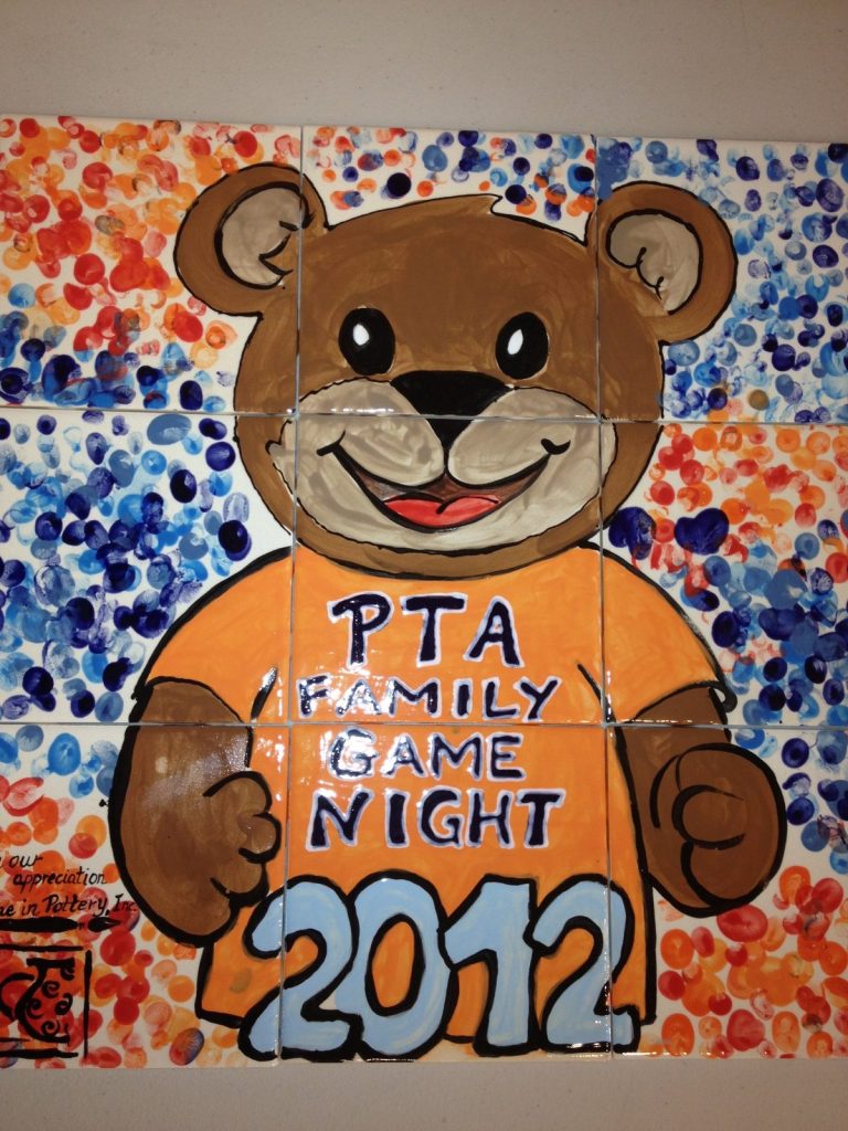 Hand-painted tile mural of a smiling bear in an orange "PTA Family Game Night 2012" shirt on fingerprint dots