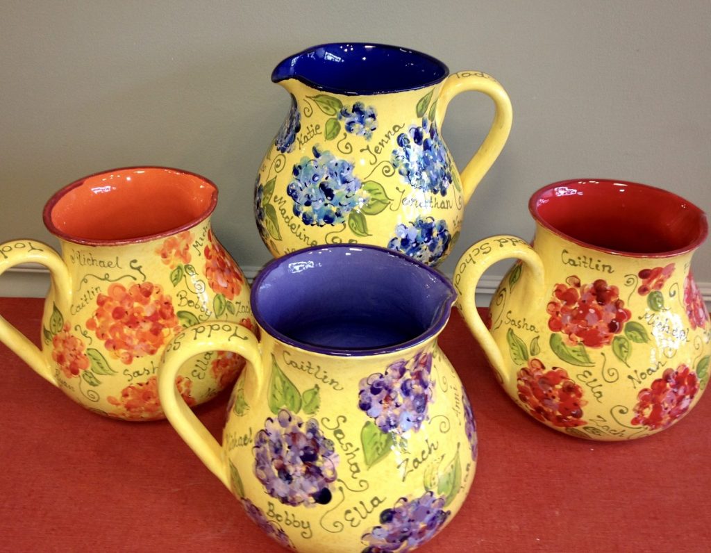 Four hand-painted pitchers with fingerprint hydrangeas and flowers in yellow, red and purple