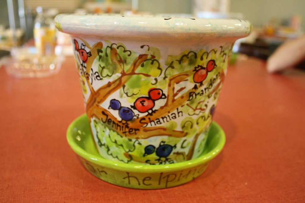 Hand-painted flowerpot and saucer with fingerprint birds on a leafy branch and children's names