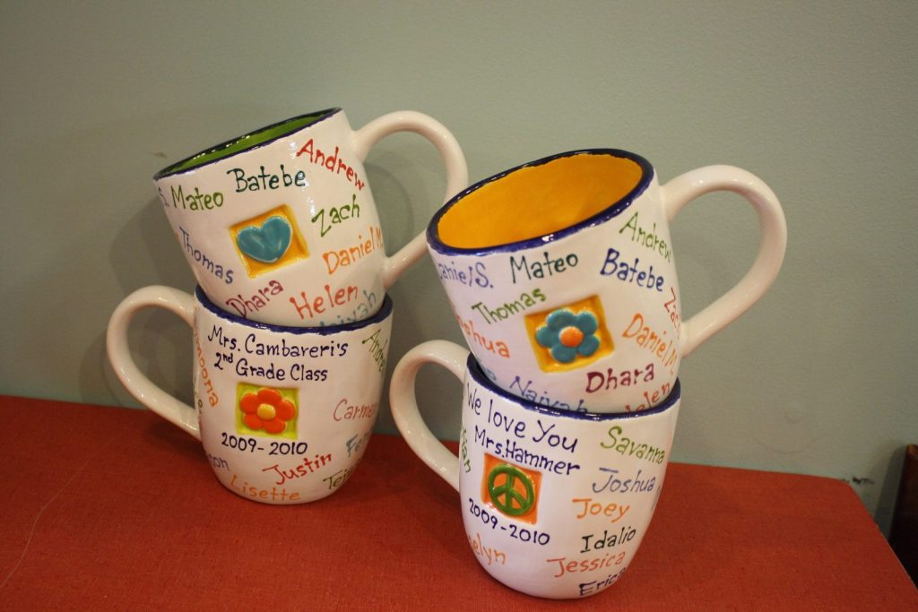 Set of four hand-painted mugs from a 2nd grade class with flower motifs and names, 2009–2010