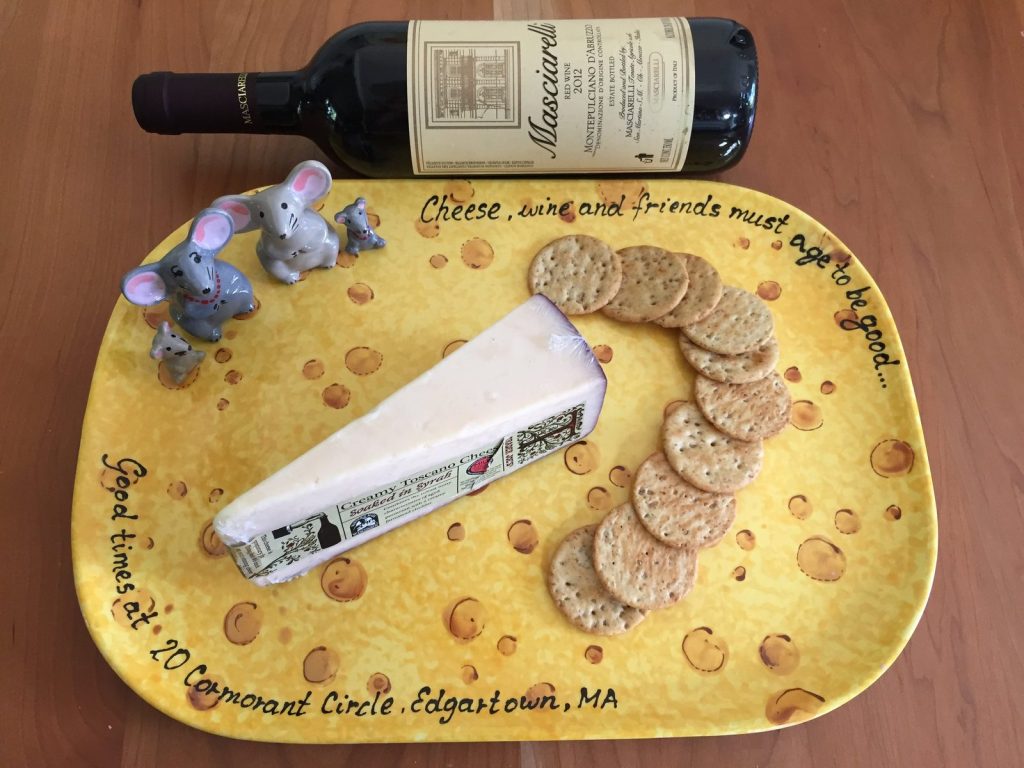 Hand-painted yellow cheese platter with a Swiss cheese pattern, shown with wine, cheese and crackers