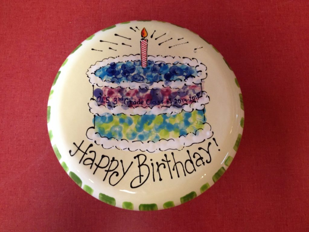 Hand-painted round "Happy Birthday!" plate with a layered fingerprint cake and a single candle