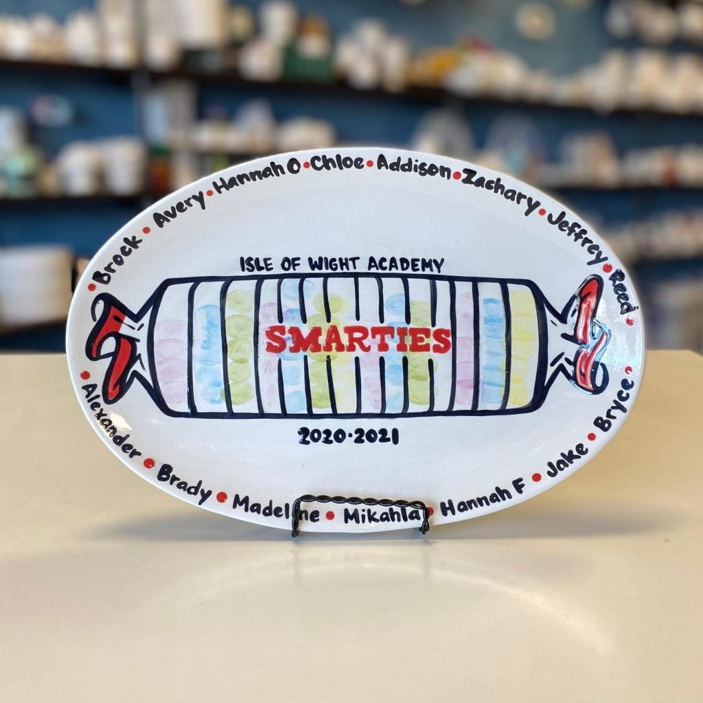 Hand-painted oval Isle of Wight Academy platter with a Smarties candy roll and student names, 2020–2021