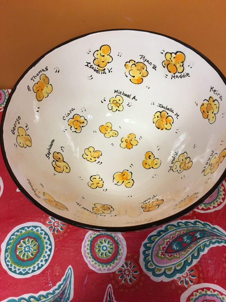 Inside of a hand-painted popcorn bowl with yellow fingerprint popcorn and children's names