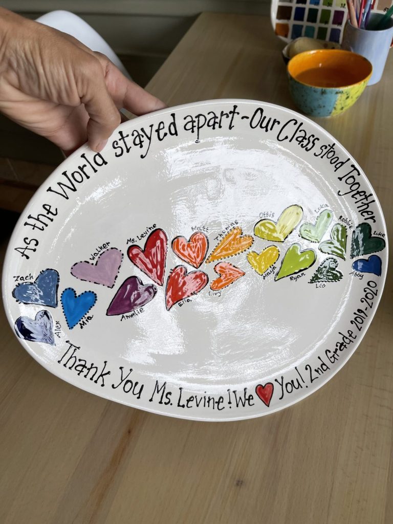 Hand-painted oval class platter of rainbow fingerprint hearts with a thank-you message, held up to show