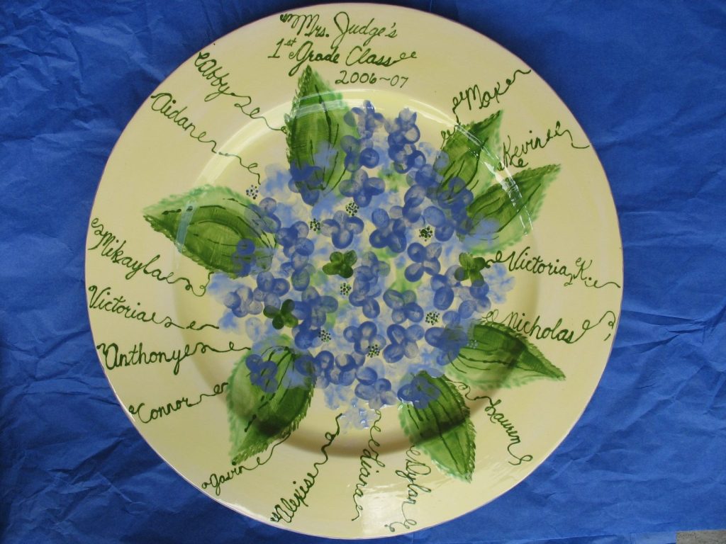 Hand-painted round 1st grade class platter with a blue fingerprint hydrangea and names on green vines