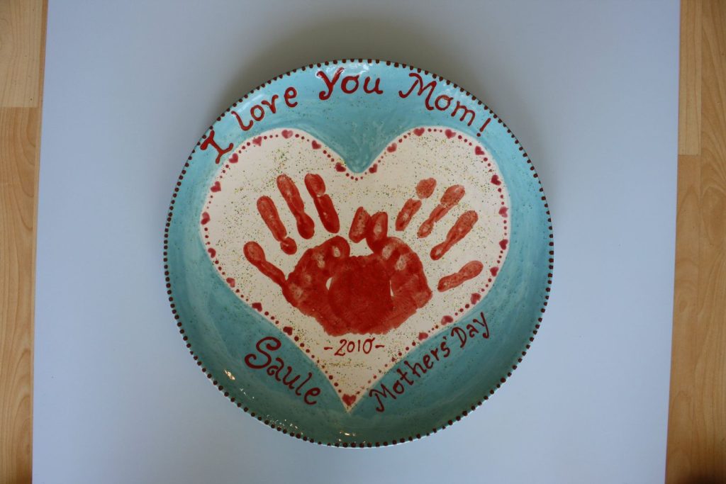 Round teal plate with a red handprint heart reading I Love You Mom