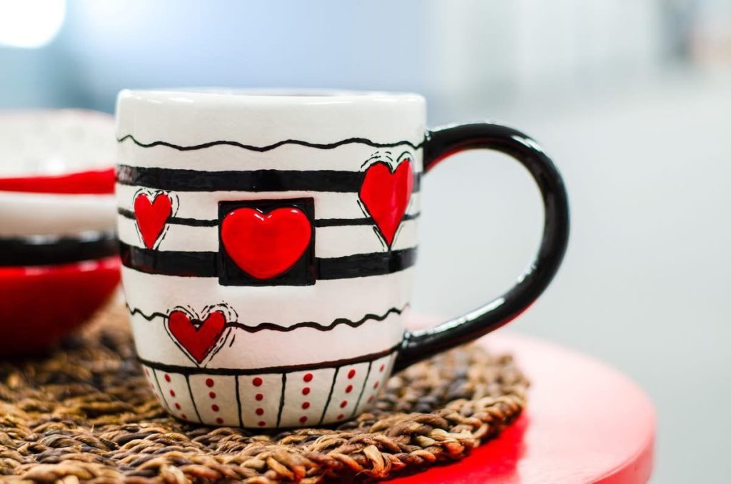 White mug with black stripes, red hearts and a black handle, hand-painted for Valentine's Day