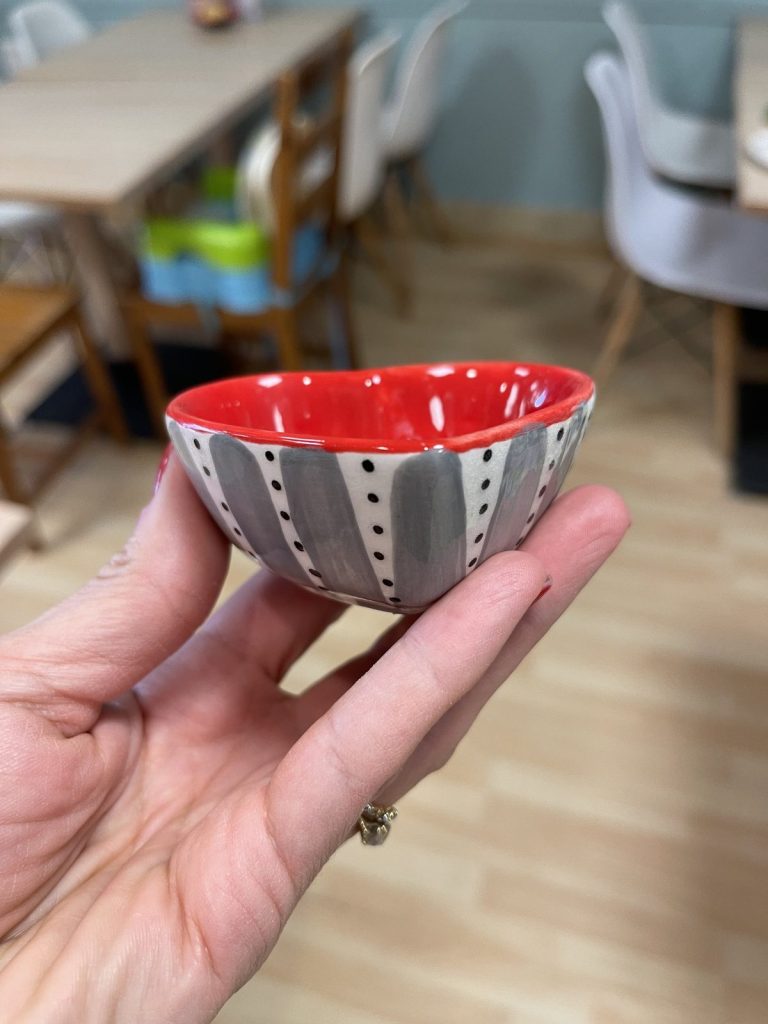 Hand-painted small heart-shaped bowl with a red interior and gray and white striped outside