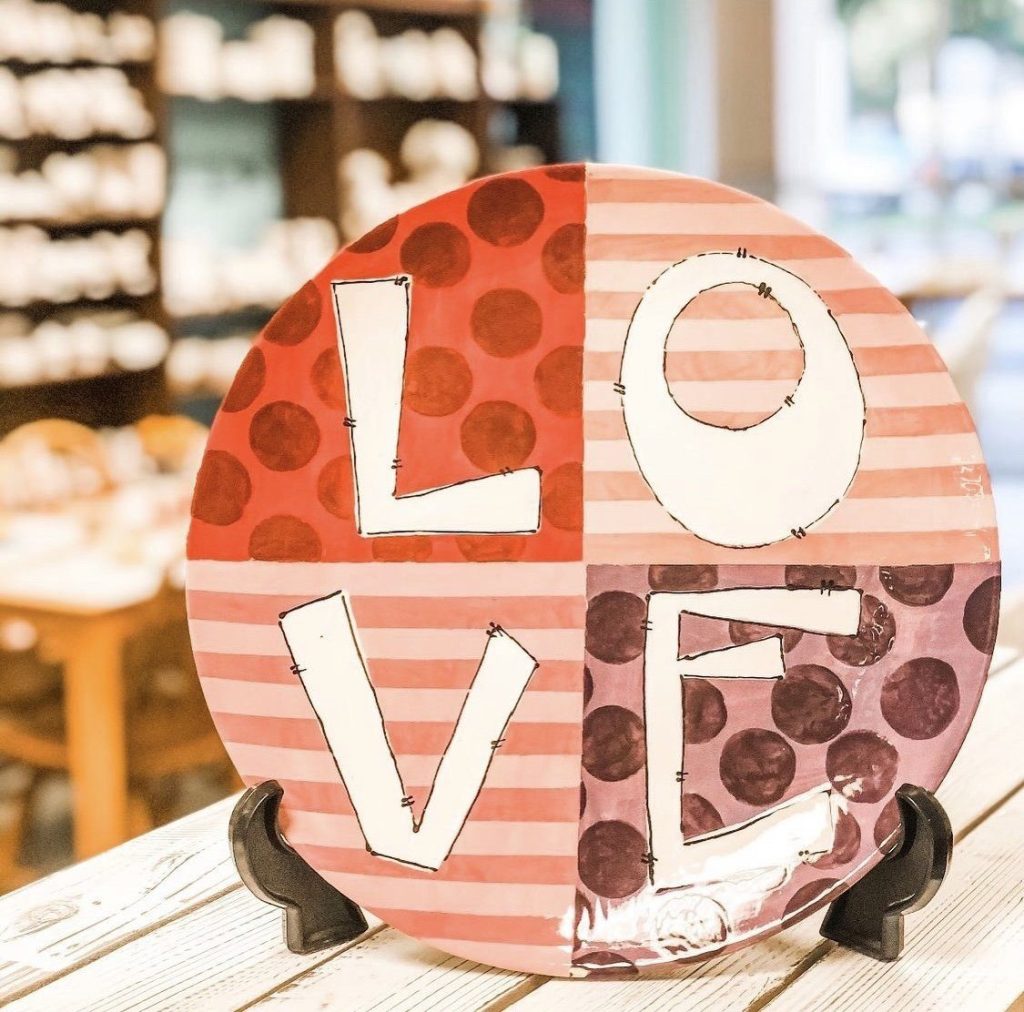 Hand-painted round plate with LOVE letters over pink striped and polka-dot quadrants