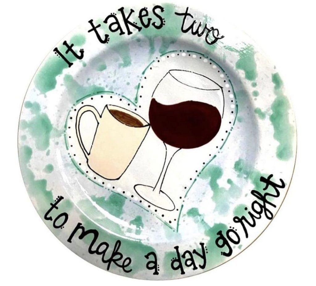 Hand-painted plate reading It takes two to make a day go right with a coffee mug and wine glass