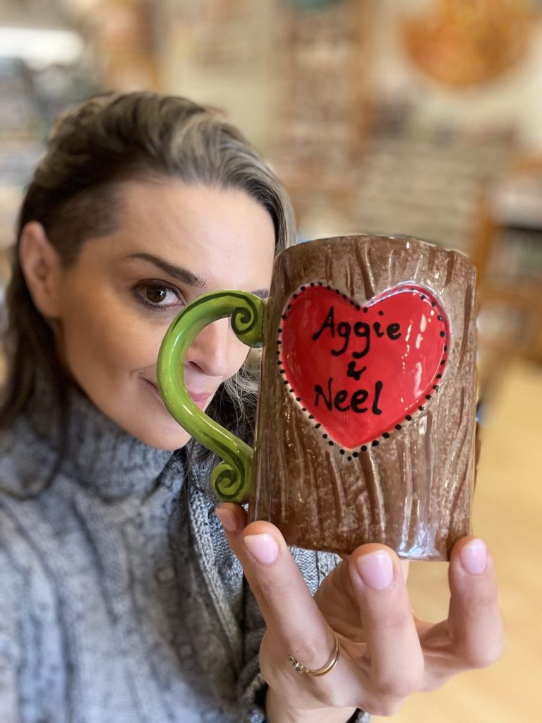 Hand-painted brown tree-bark mug with a red heart bearing a couple's names and a green twig handle
