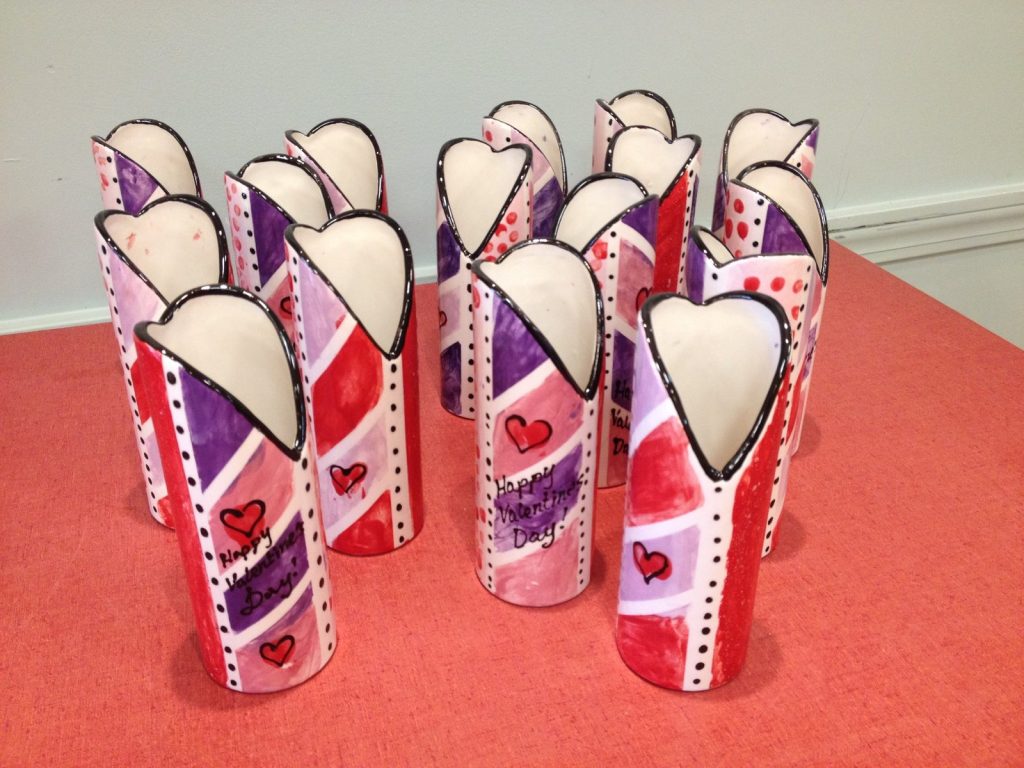 Group of hand-painted heart-topped bud vases in pink, purple, and red with hearts and dots