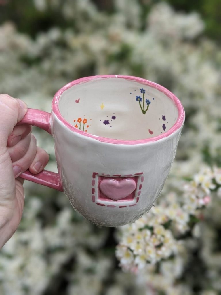 Hand-painted white mug with a raised pink heart, pink rim, and tiny flowers inside
