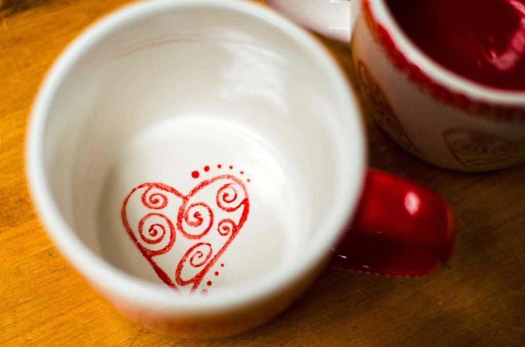 Hand-painted white mug interior with a red swirl heart at the bottom and a red handle
