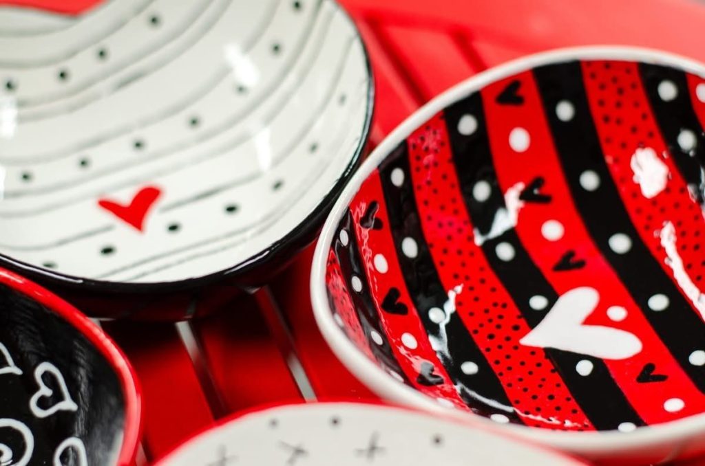 Several hand-painted heart bowls in black, white, and red stripes and dots with small hearts